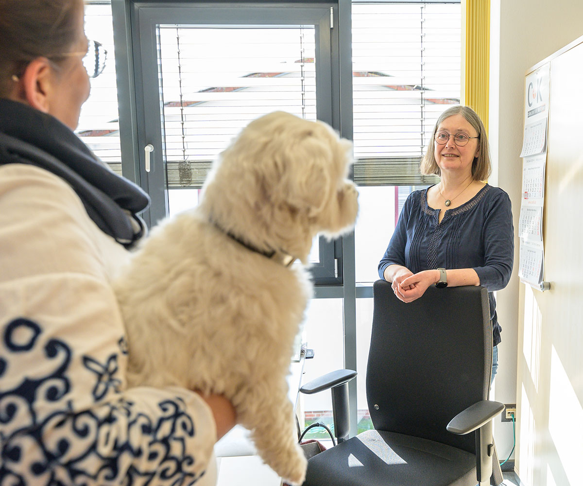 Arbeitsalltag bei C+K Bürohund auf dem Arm, Blick zu Frau Schleeßelmann